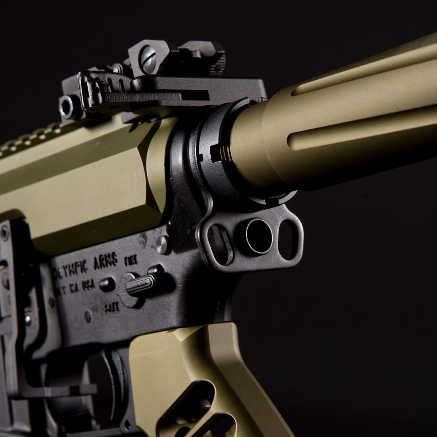 Close-up of Olympic Arms AR-style rifle with FDE and black finish, highlighting tactical components.