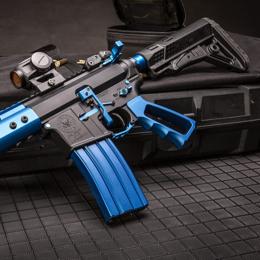 Custom blue and black AR-15 rifle with tactical scope on black surface.