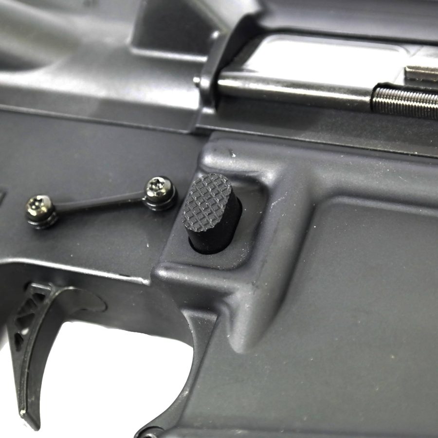 Close-up of AR-15 trigger, safety selector, and assembly screws in matte black finish.