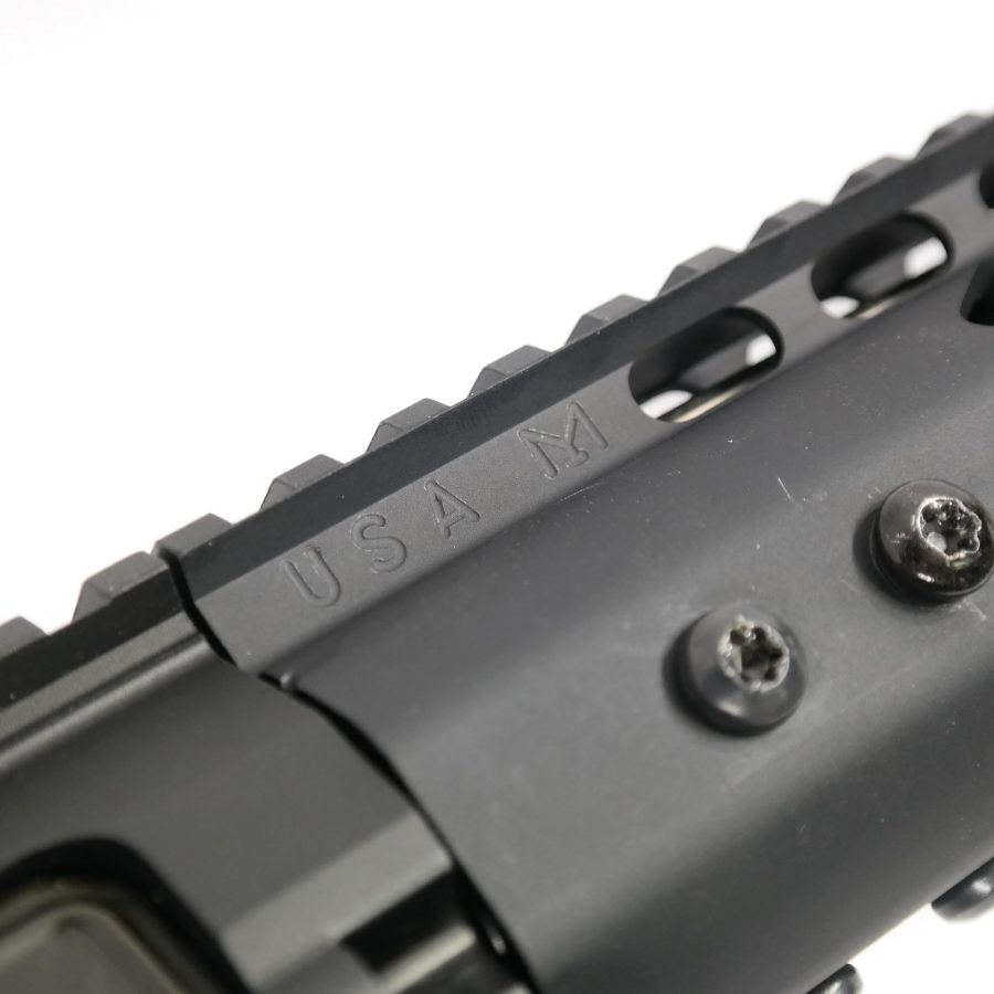 Close-up of black Picatinny rail on rifle, engraved USA W, with hex screws.