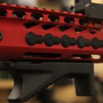 Close-up of a vibrant red AR-15 handguard showcasing mounting slots and precision cutouts.