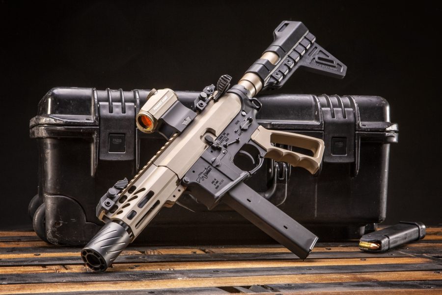 Custom AR-15 pistol with optics and tactical accessories on wooden surface and tactical case.