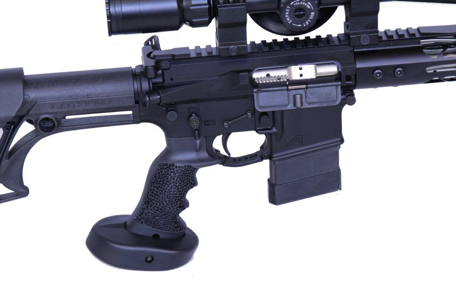 Close-up of black AR-style rifle with ergonomic grip, adjustable stock, and mounted optic.