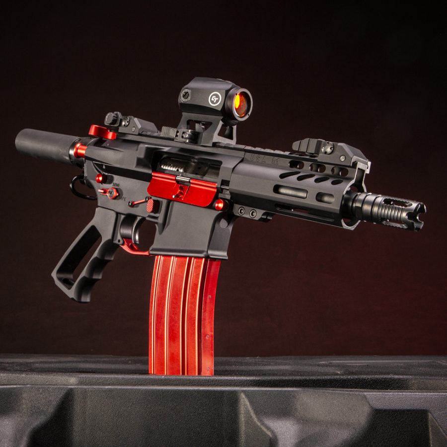 Custom AR-style firearm with red accents on a black frame, highlighted professionally.