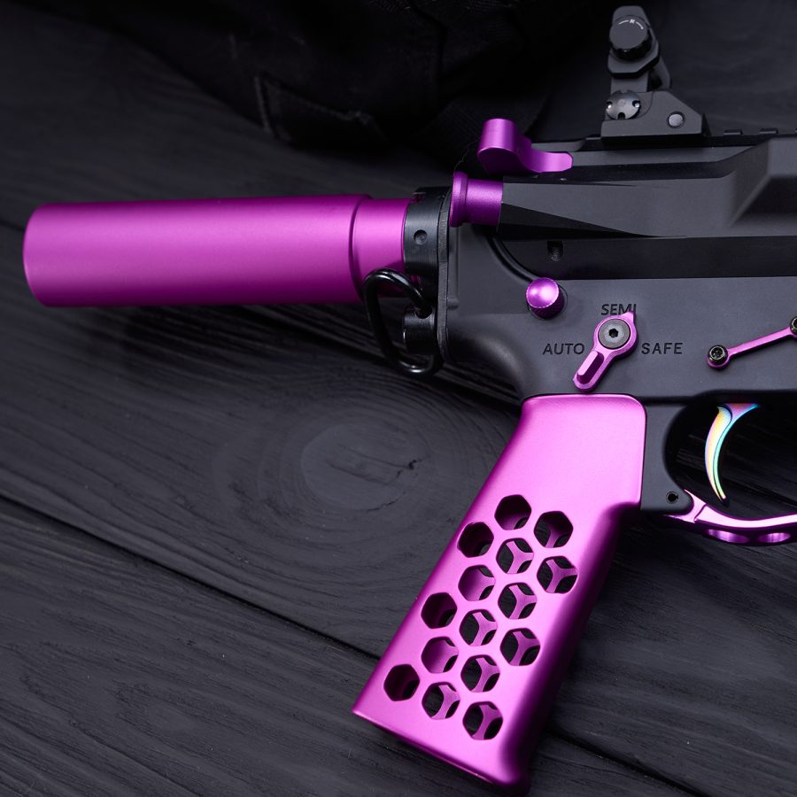Custom AR-style rifle with purple accents, honeycomb grip, on dark wood surface.