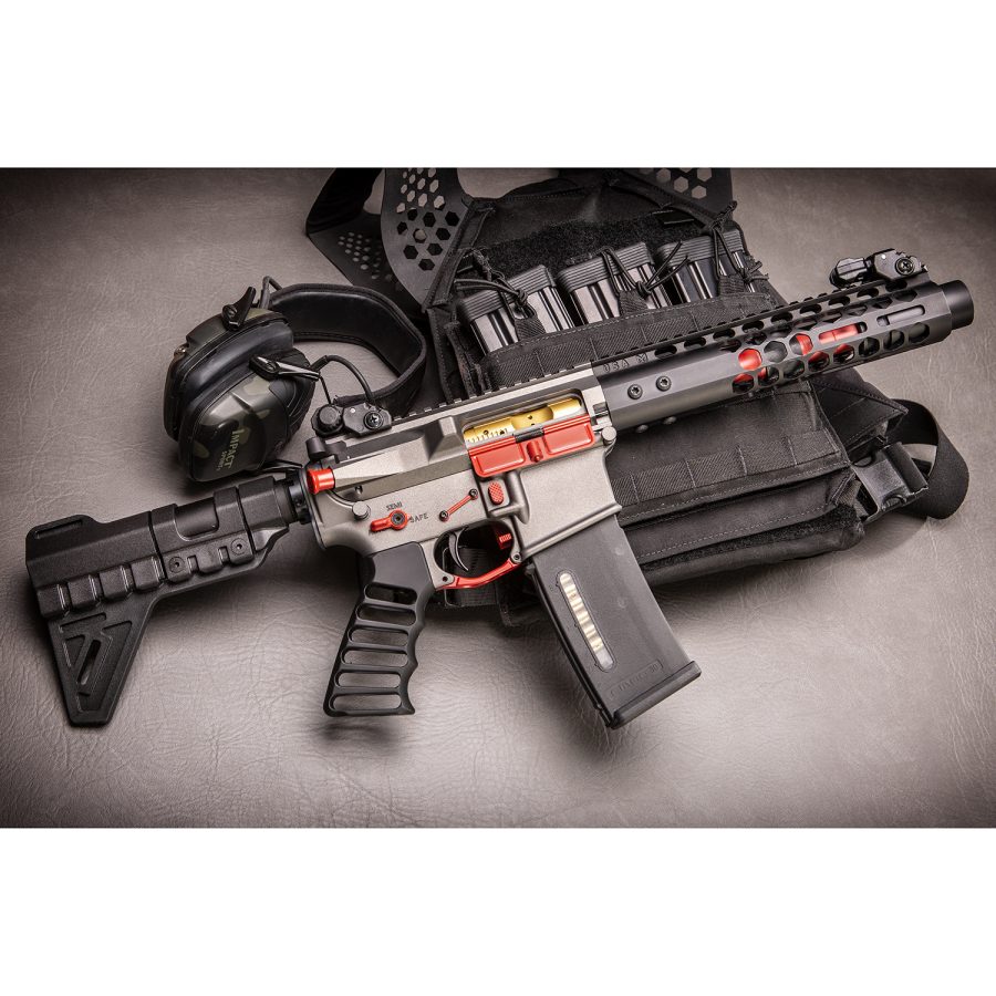 Modern black tactical rifle with red accents, collapsible stock, optic sight, and tactical gear.