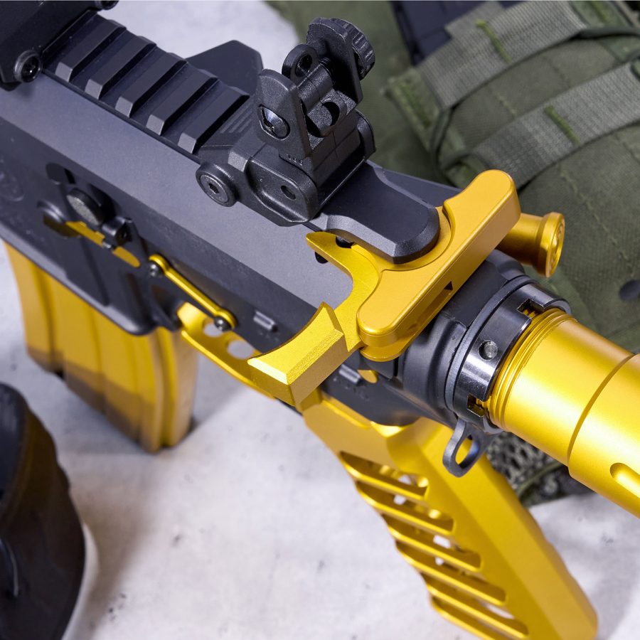 Custom black and gold tactical rifle with detailed enhancements and tactical gear in the background.