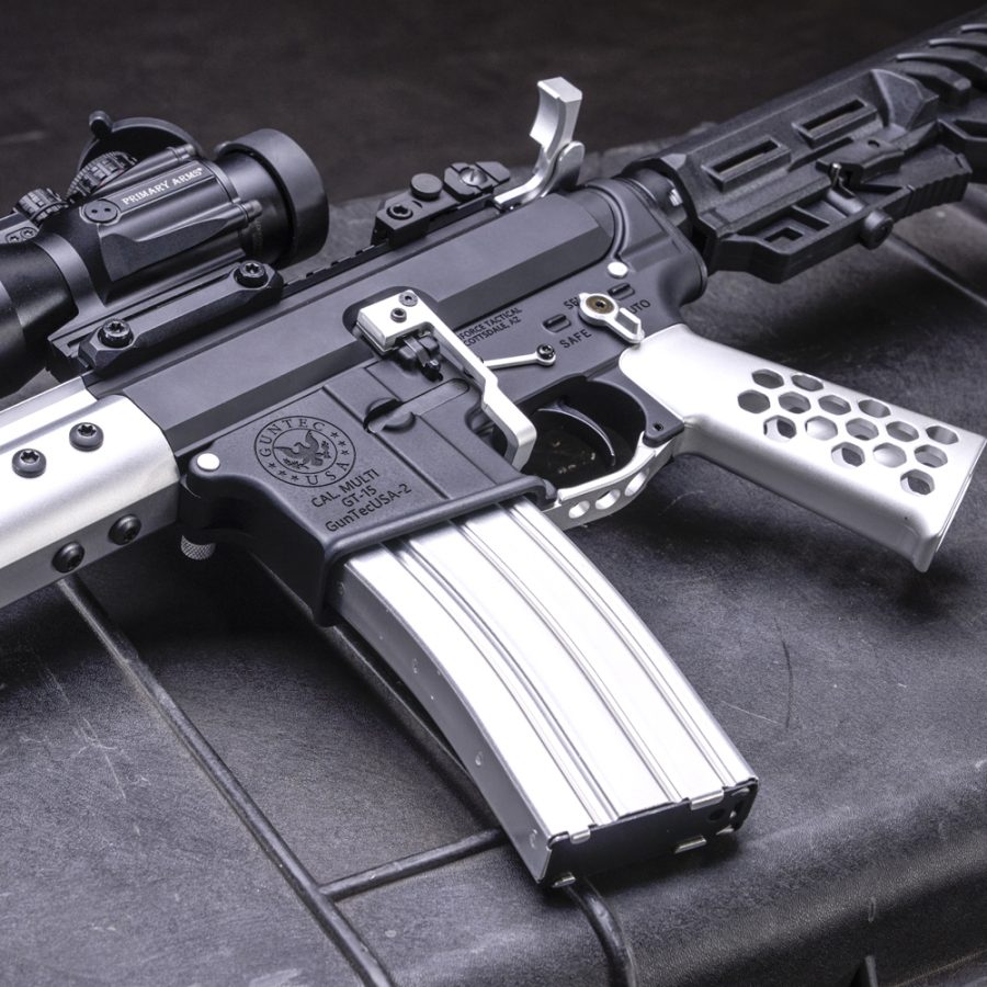 Modern tactical rifle with custom optics, silver magazine, perforated grip; precision-crafted components.