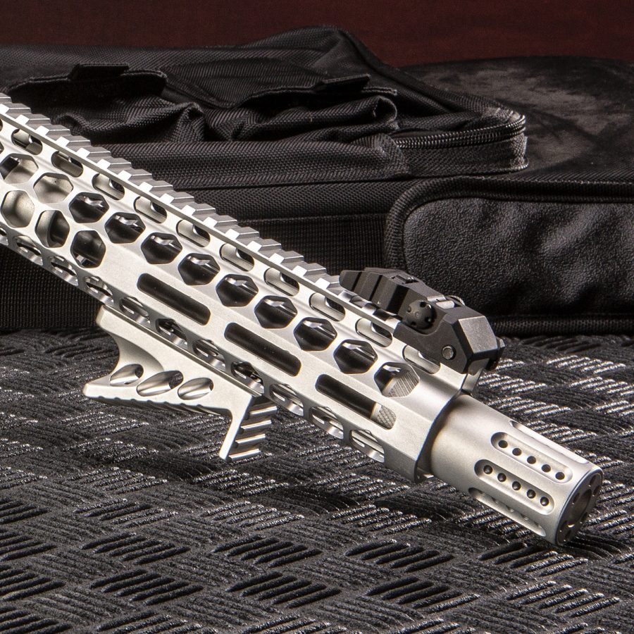 Close-up of a tactical silver AR rifle handguard with skeletonized design and muzzle device.