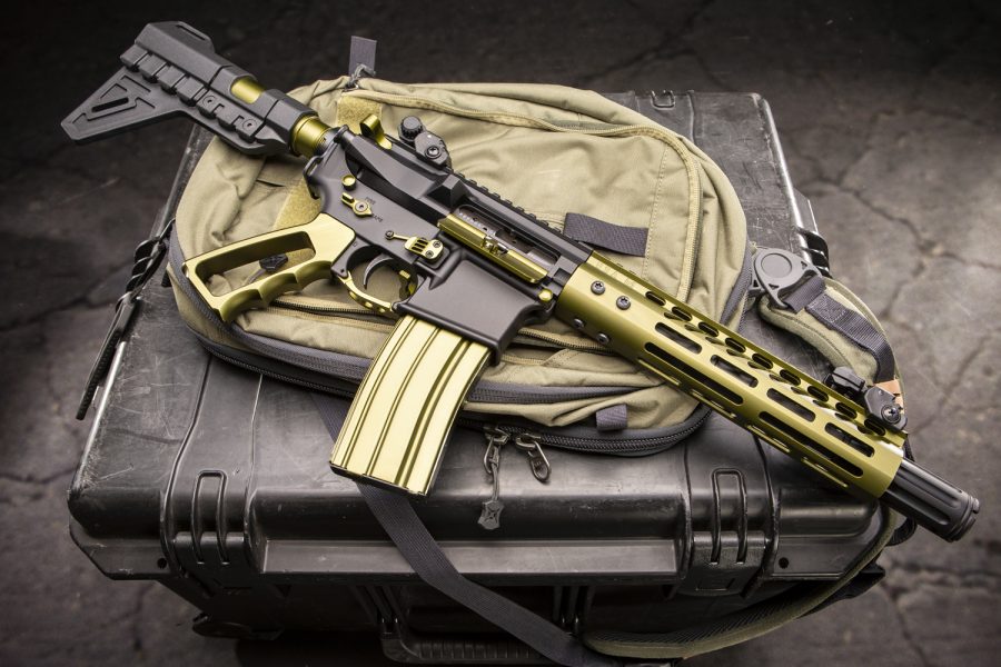 Olive green and black AR rifle on tactical bag and case, modern gear showcase.