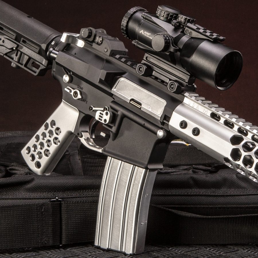 Custom AR-15 with honeycomb handguard, tactical scope, silver and black finish on black case.
