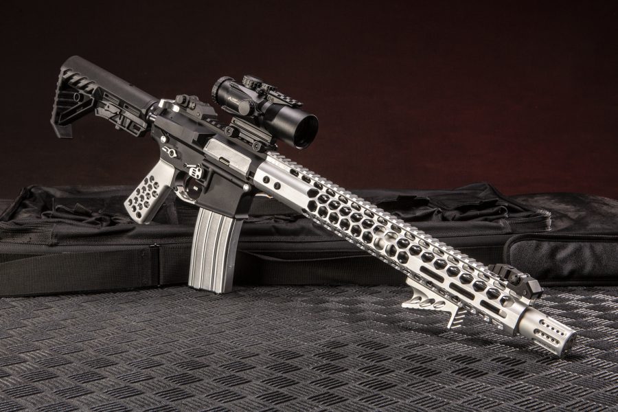 Custom AR-Style Rifle: Black upper, silver/tan handguard, tactical scope on textured surface.