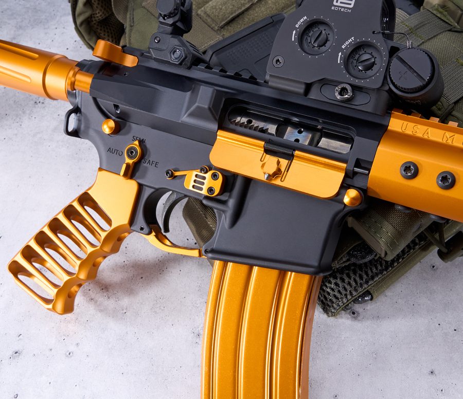 Custom gold/black AR-platform firearm with premium components and intricate craftsmanship.