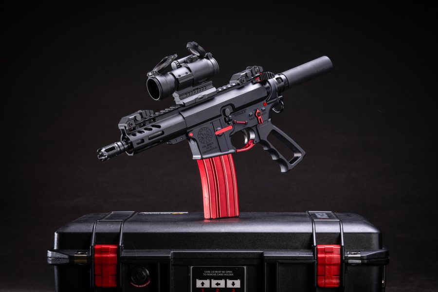 Compact AR-style pistol with red magazine and case accents displayed on a black background.