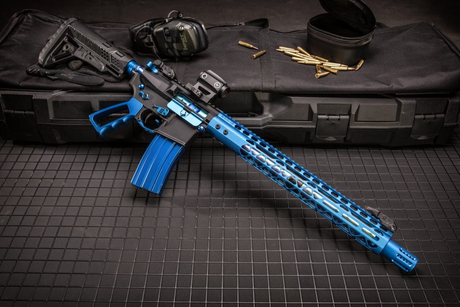 Custom blue AR rifle with accessories on tactical case, highlighted on dark grid surface.