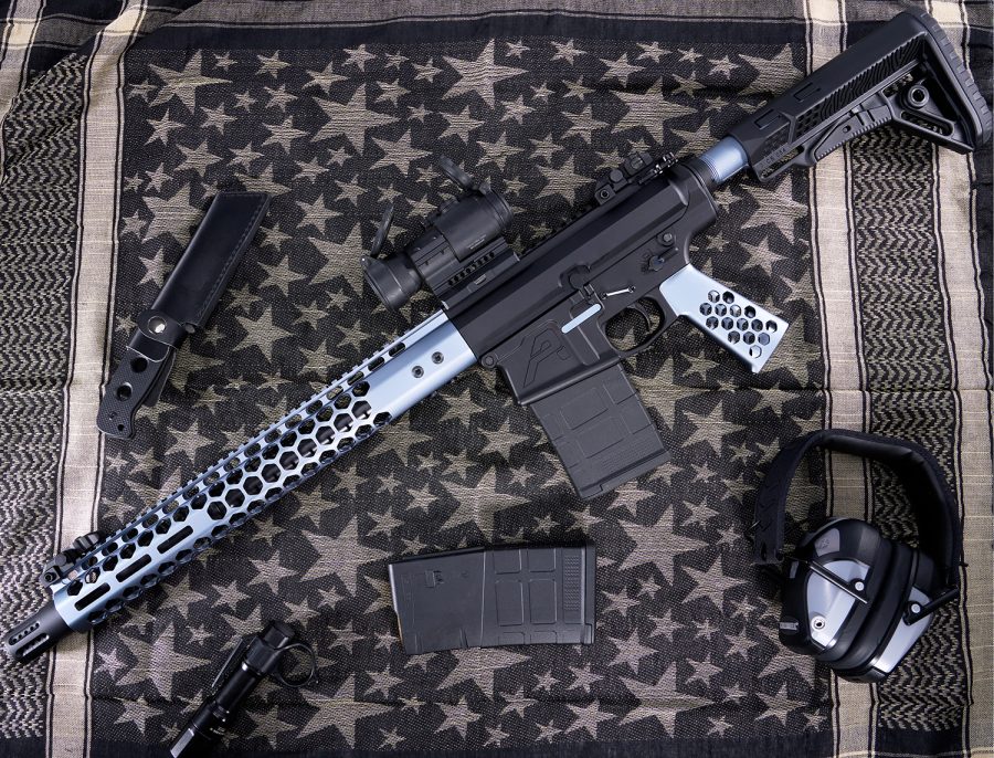 Modern AR-style rifle with accessories on star-patterned cloth evoking American flag symbolism.