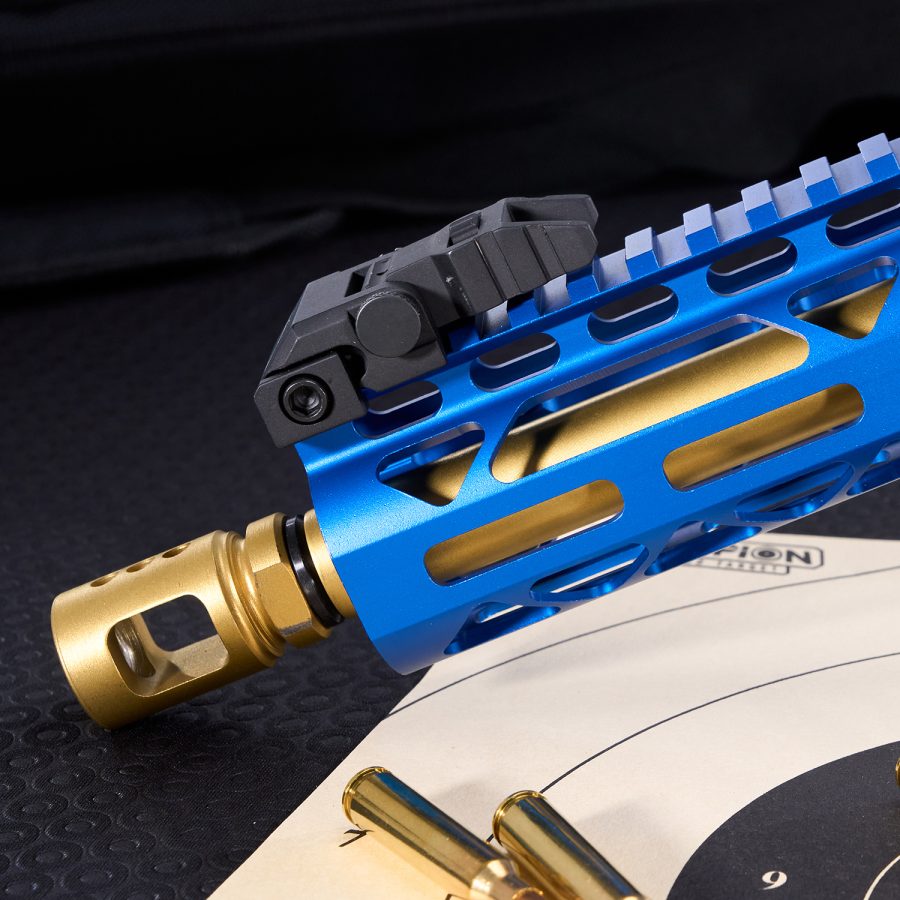 Blue anodized rail with black sight and gold muzzle device on a firearm.