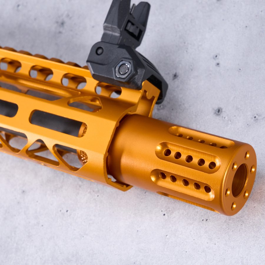 Gold anodized muzzle device with black sight on M-LOK handguard, precise engineering.