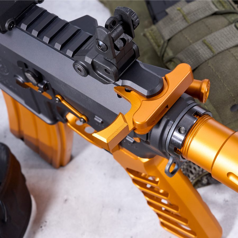 Custom two-tone black and orange-gold tactical firearm with detailed receiver and Picatinny rail.