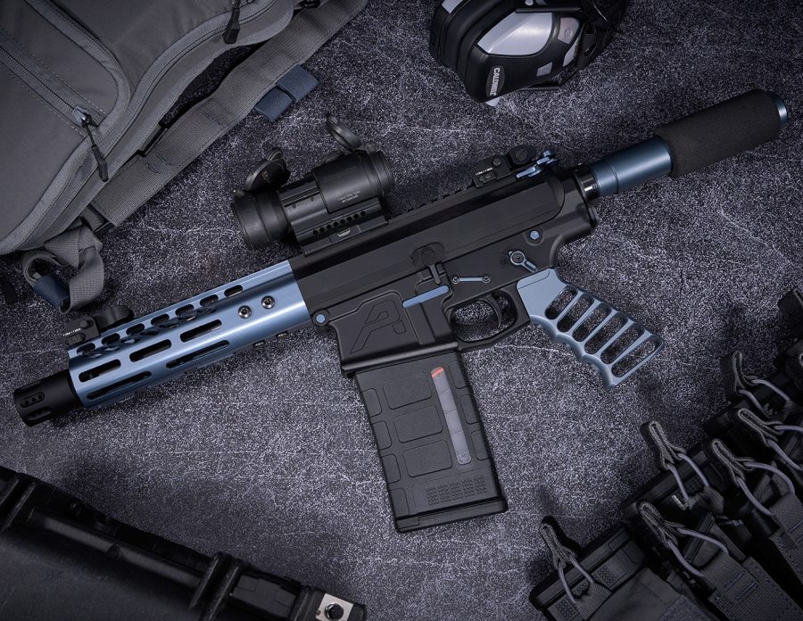 High-end tactical AR pistol with silver handguard, optic sight, surrounded by tactical gear.