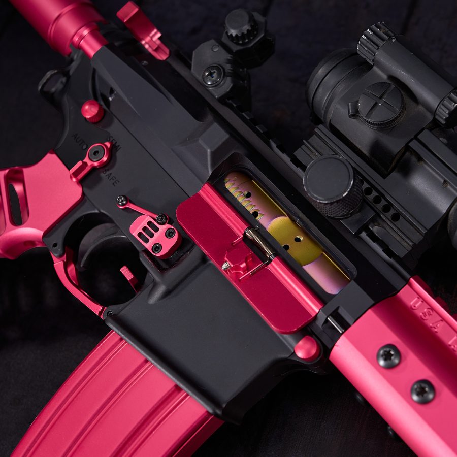 Customized AR-style rifle in black and metallic pink with tactical modifications.