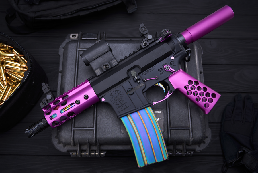 Custom black and purple AR-style rifle with iridescent magazine on a protective case.