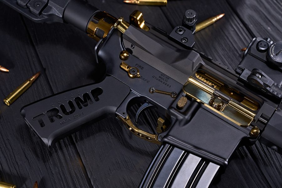 Custom black and gold AR-15 rifle with Trump MAGA 2024 engravings, brass ammo shown.